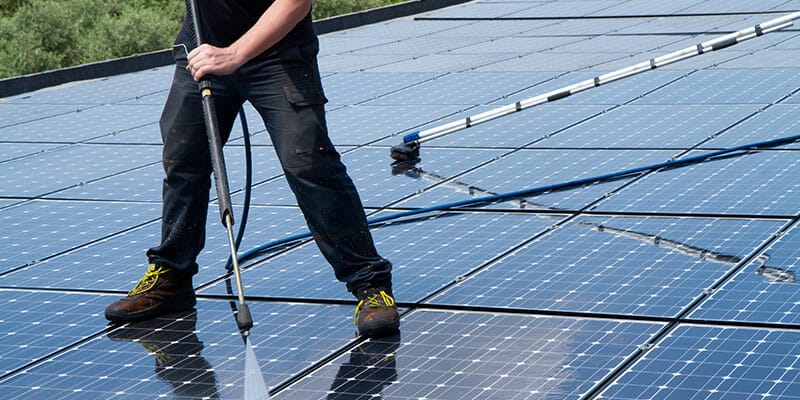A man is cleaning solar photovoltaic panel with water.